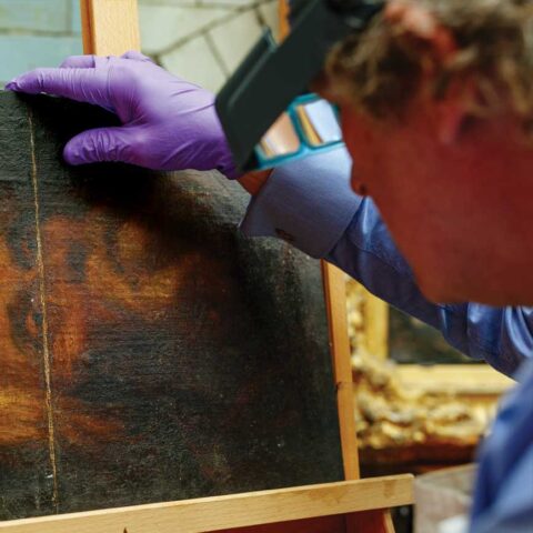 Conservator inspecting oil painting for valuations