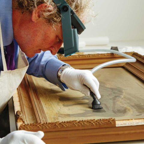 Conservator vaccuumming dust on painting - how to protect paintings from dust