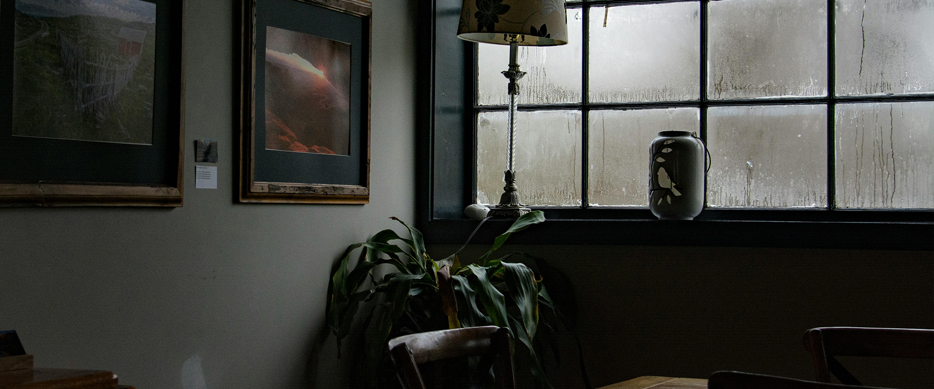 Framed photographs and artworks on wall close to window condensation.